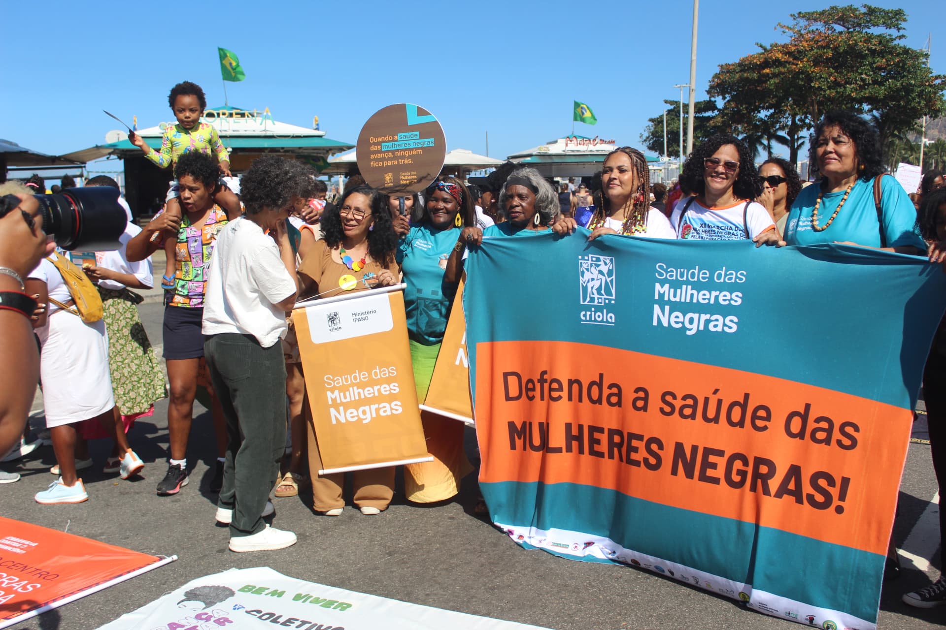 Grupo de mulheres na marcha segurando faixas da Criola pela saúde das mulheres negras