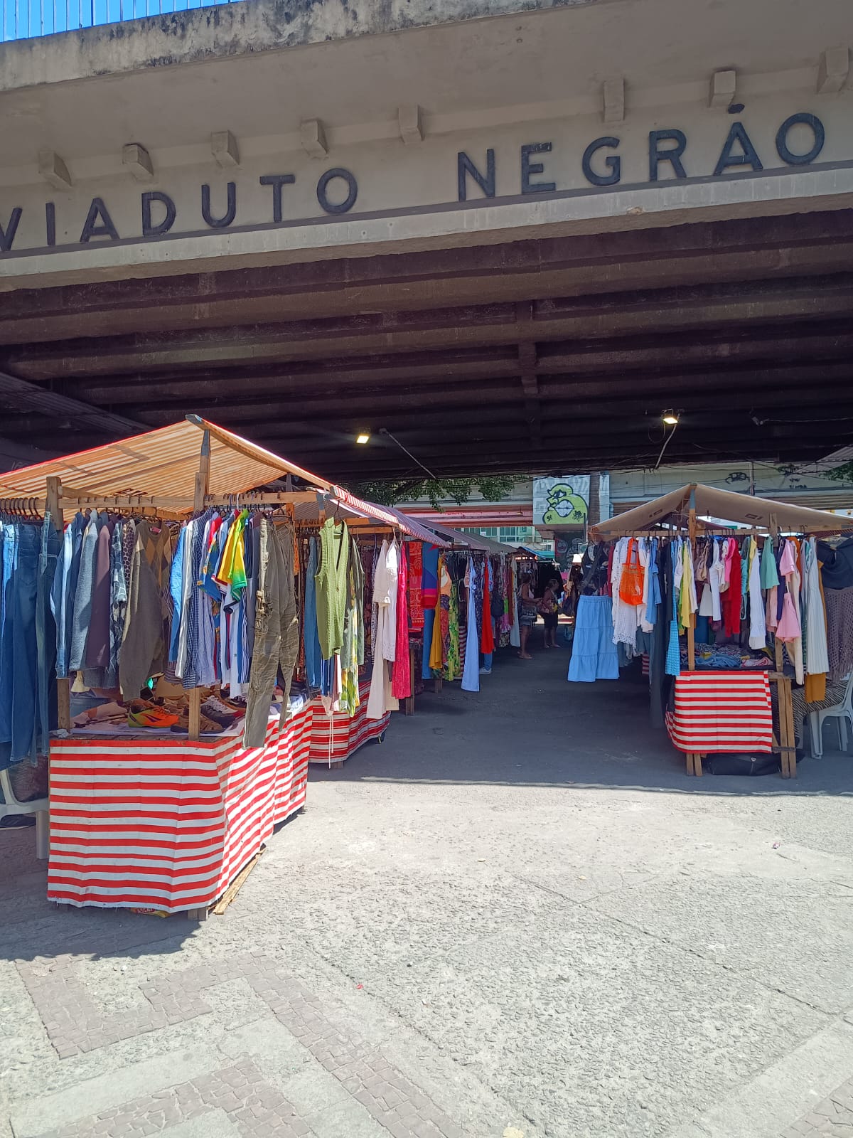Feira popular com barracas de roupas sob o Viaduto Negrão