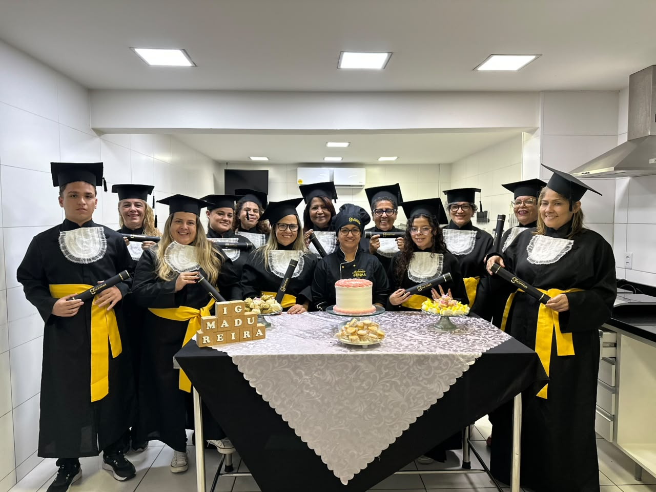 Formatura de turma de gastronomia com alunas de beca segurando seus diplomas